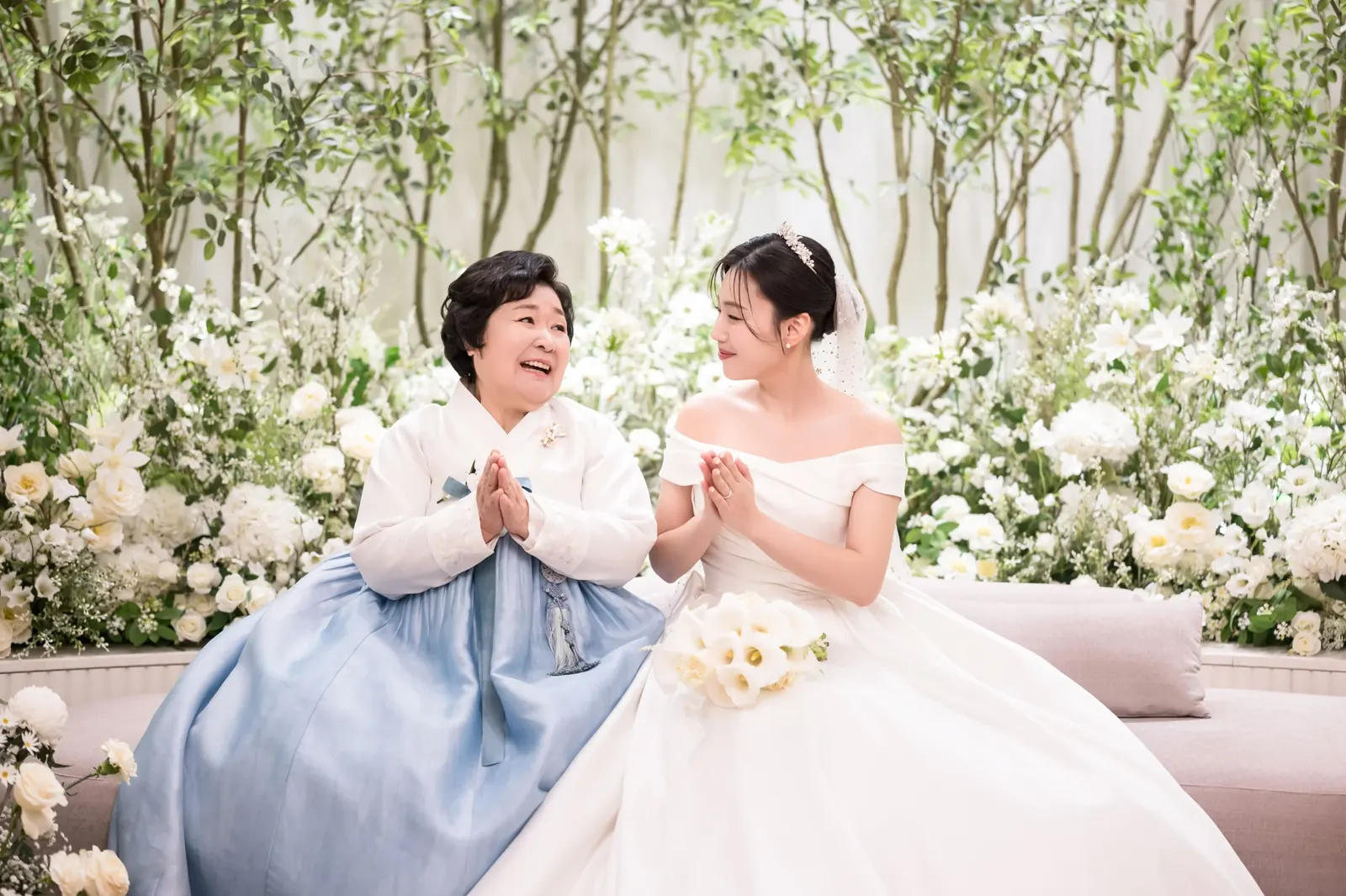 세인트메리엘 결혼식사진 — 대기실 소파에서 하늘색 한복 입은 어머니와 마주 보며 웃는 신부