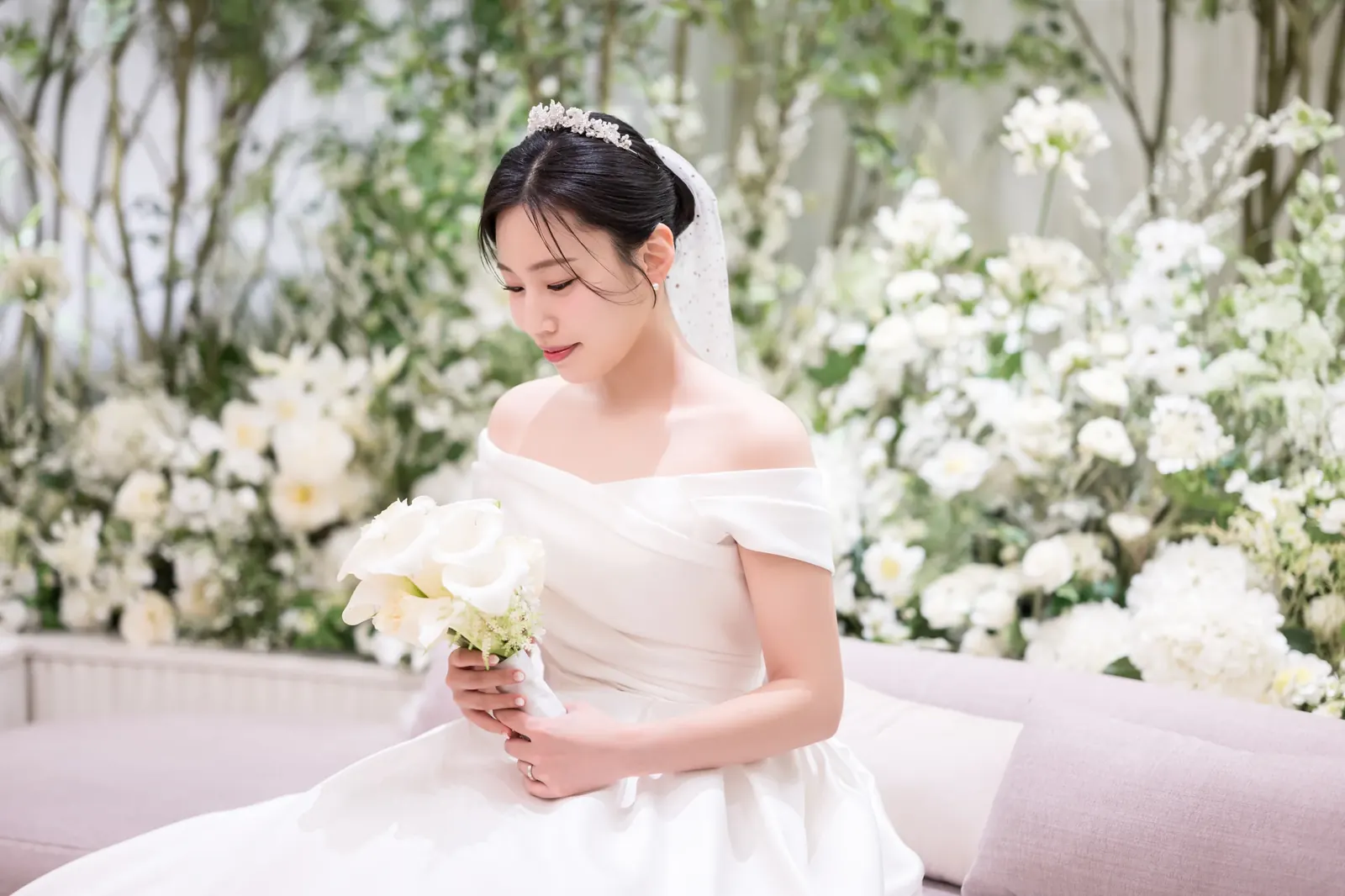 신부대기실 단독 컷 예시 — 서울 강남구 세인트메리엘 흰 꽃장식 소파에서 칼라 부케를 들고 미소 짓는 신부