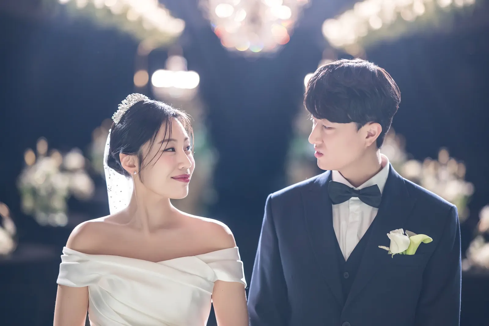 세인트메리엘 결혼식사진 — 빛망울 배경 앞에서 서로를 바라보는 신랑 신부