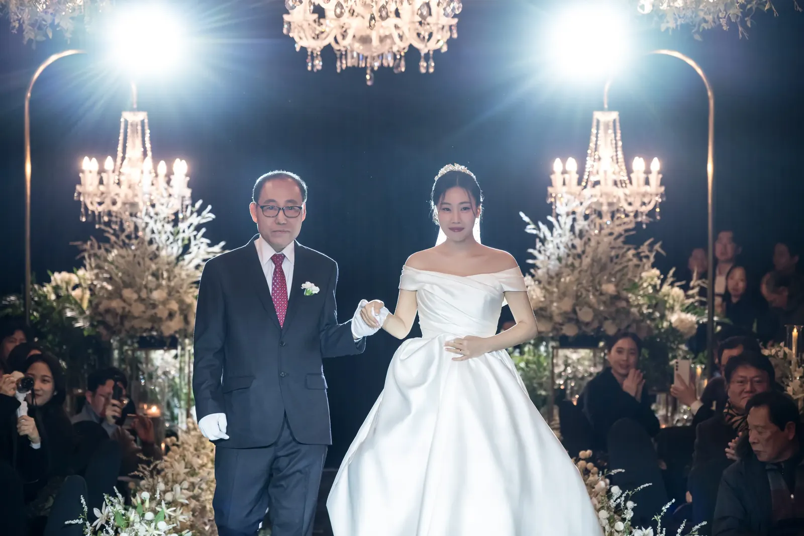 세인트메리엘 결혼식사진 — 샹들리에 조명 아래 아버지 팔짱을 끼고 입장하는 신부