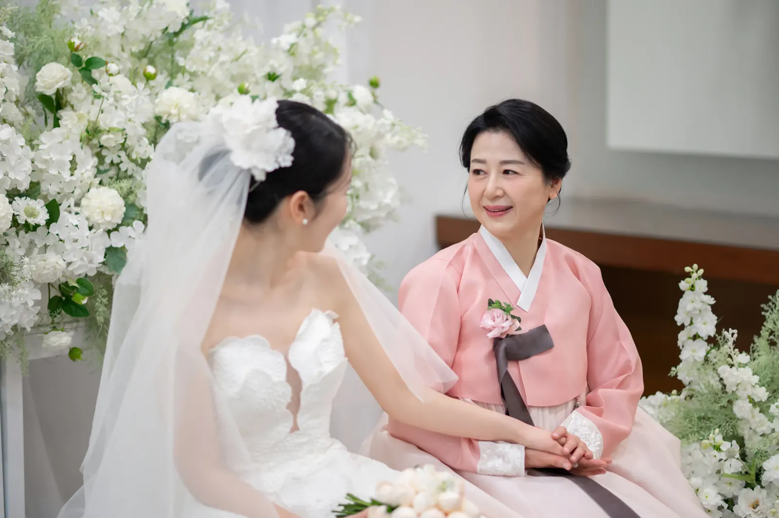 삼성서초사옥 결혼식사진 — 대기실에서 분홍 한복 입은 어머니와 마주 보며 웃는 신부