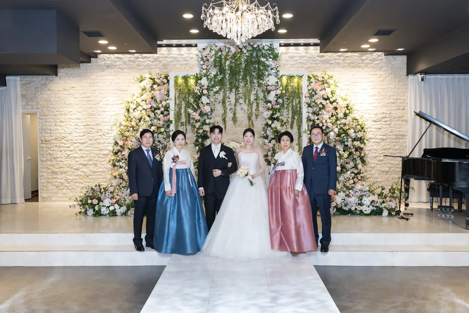 원판 가족사진 예시 — 서울 양재 브라이드밸리 샹들리에 아래 파랑·분홍 한복 혼주와 나란히 선 신랑 신부