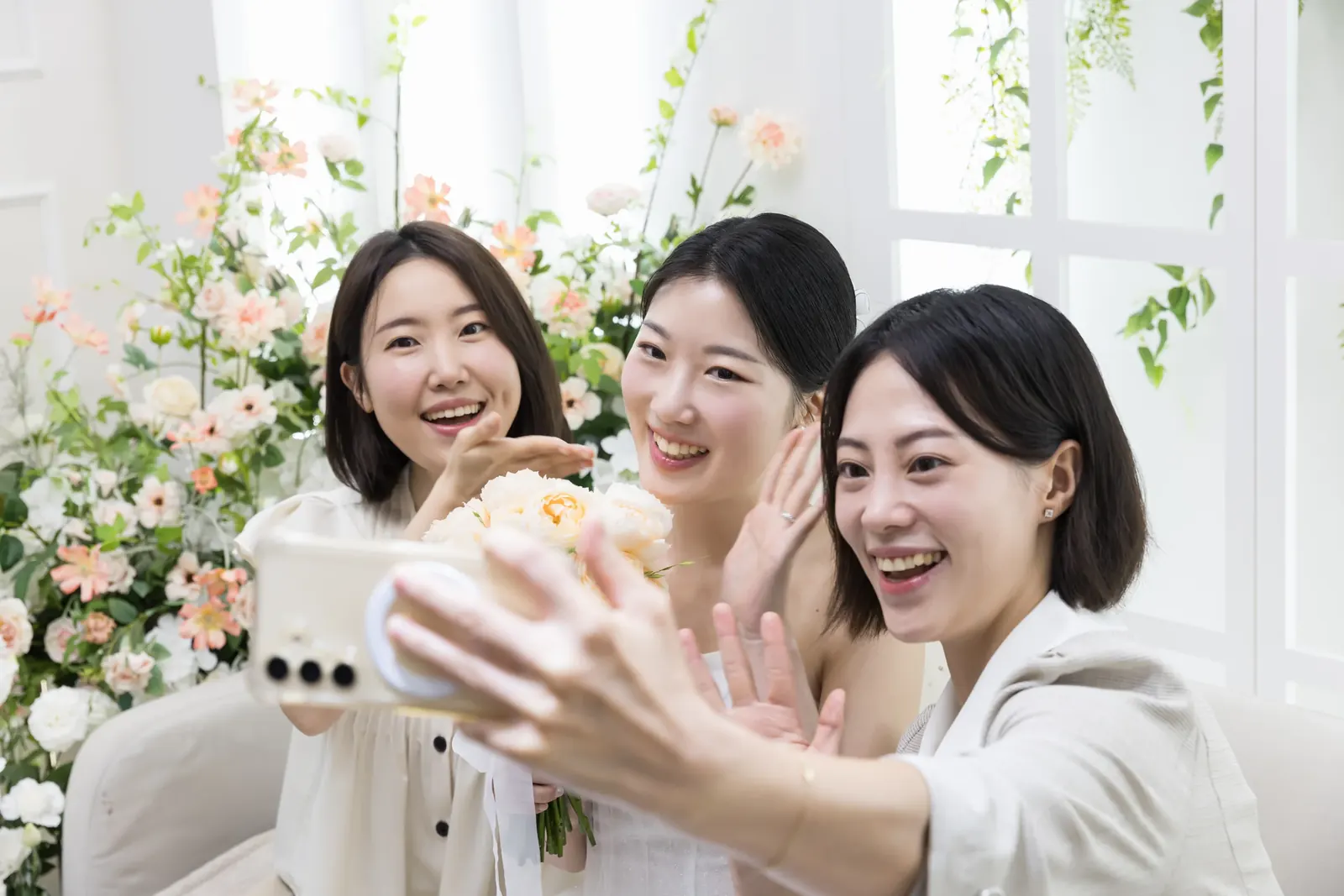 가까운 친구와의 결혼식사진 — 서울 양재 브라이드밸리 신부대기실에서 휴대폰으로 셀카를 찍는 신부와 친구 두 명